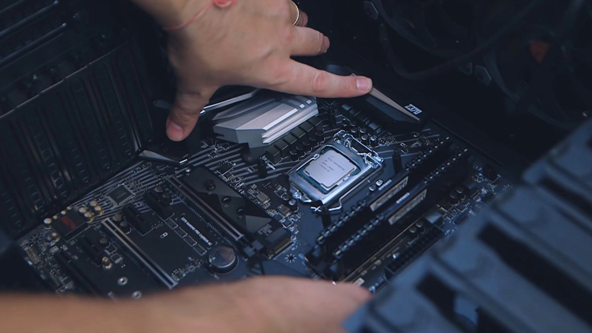 Handen die een moederbord met processor en geheugen in een pc-behuizing plaatsen